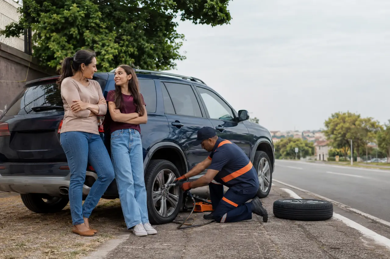 Mãe e filha recebendo assistência para trocar um pneu furado